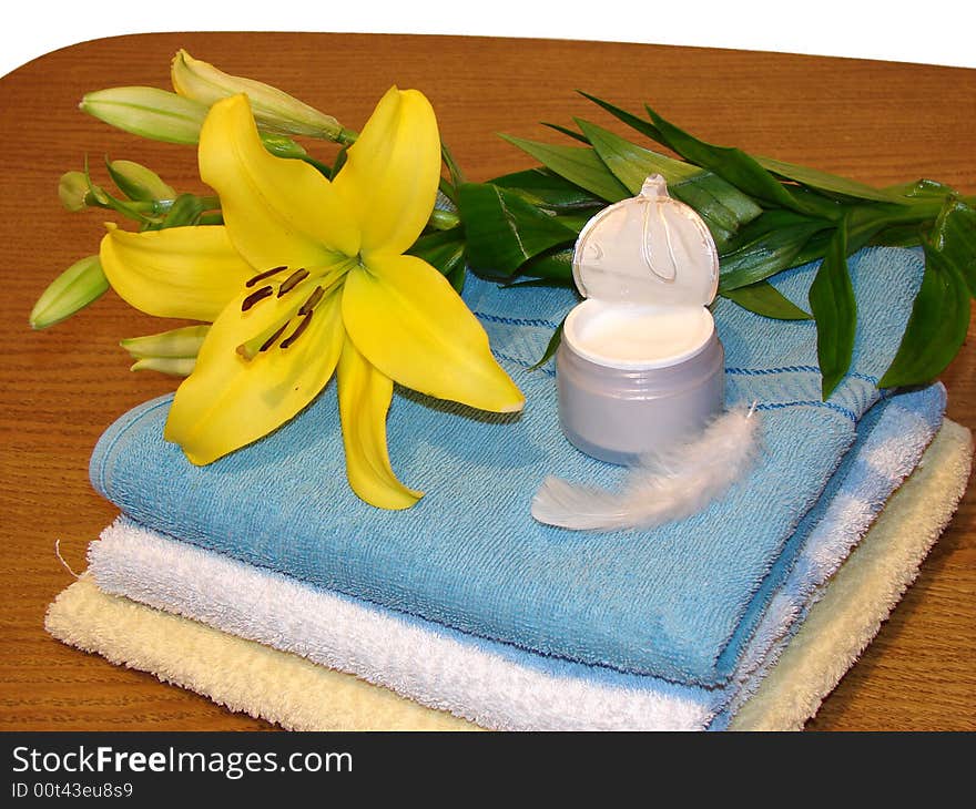 Towels, yellow flower, cream, and white feather as a concept of beauty, massage and alternative medicine.