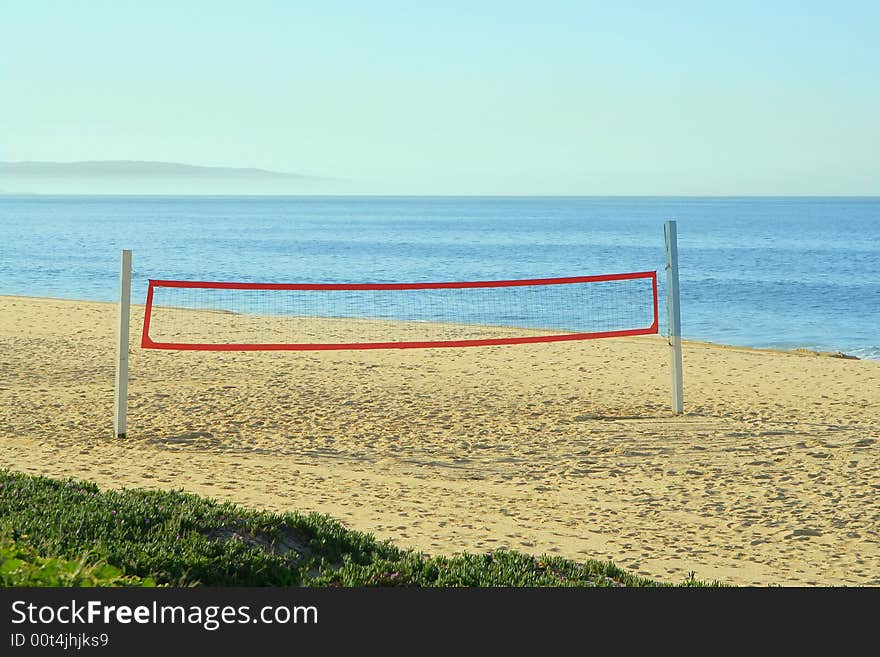 A beach volleyball net on the beach at the ocean