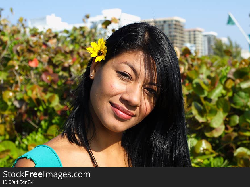 Woman looking at the camera and a yellow flower behind her ear. Woman looking at the camera and a yellow flower behind her ear.