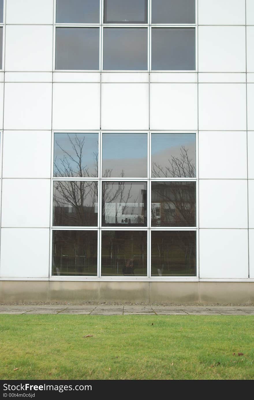 Shot of an office building with tree reflection. Shot of an office building with tree reflection.