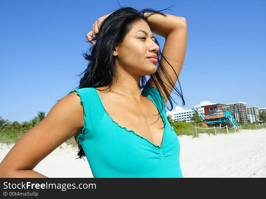 Woman at the beach with her hand on her head.