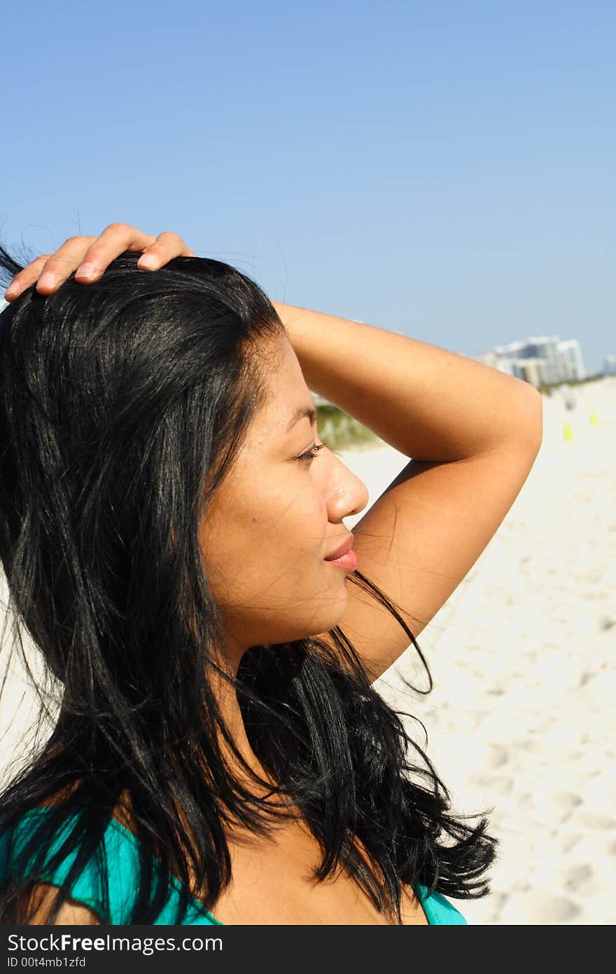 Woman at the beach with her hand on her head.