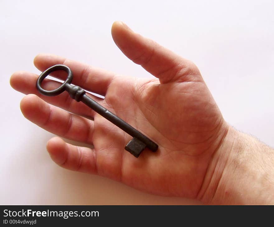 Right hand holding a vintage key on white background