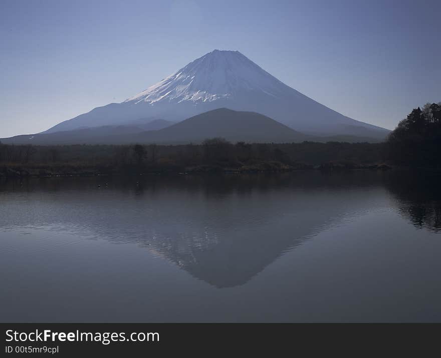 Winter view of Mount Fuji with mist and reflections in a lake. Winter view of Mount Fuji with mist and reflections in a lake