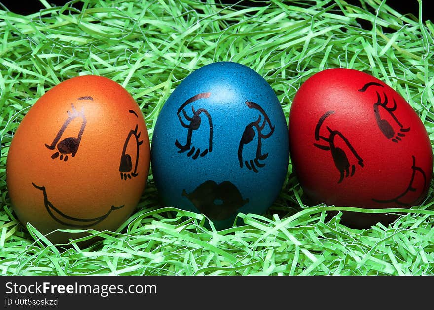 Colored eggs are standing with green on the black background. Colored eggs are standing with green on the black background