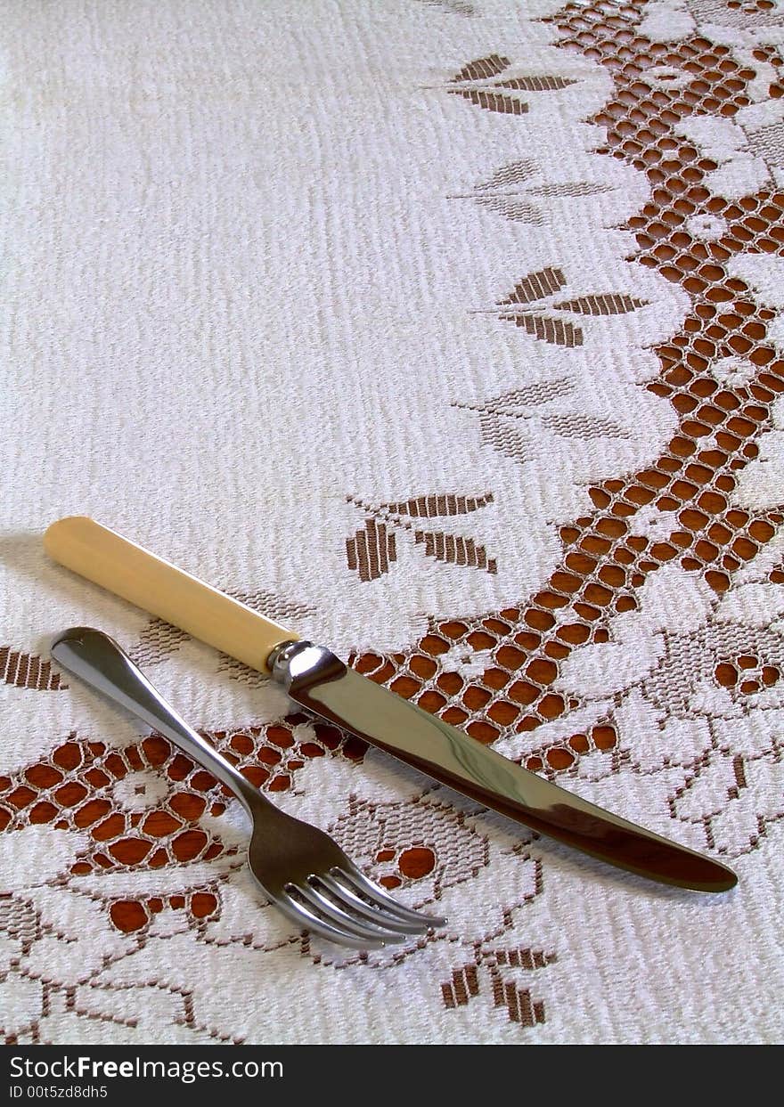 A fork and a bone-handled knife lying on a lace-work tablecloth. A fork and a bone-handled knife lying on a lace-work tablecloth.