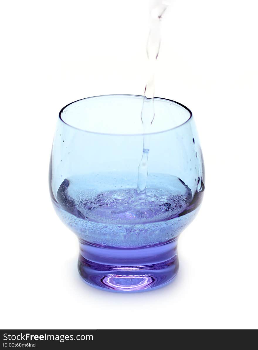 Stream of water falling into purple glass isolated on white. Stream of water falling into purple glass isolated on white