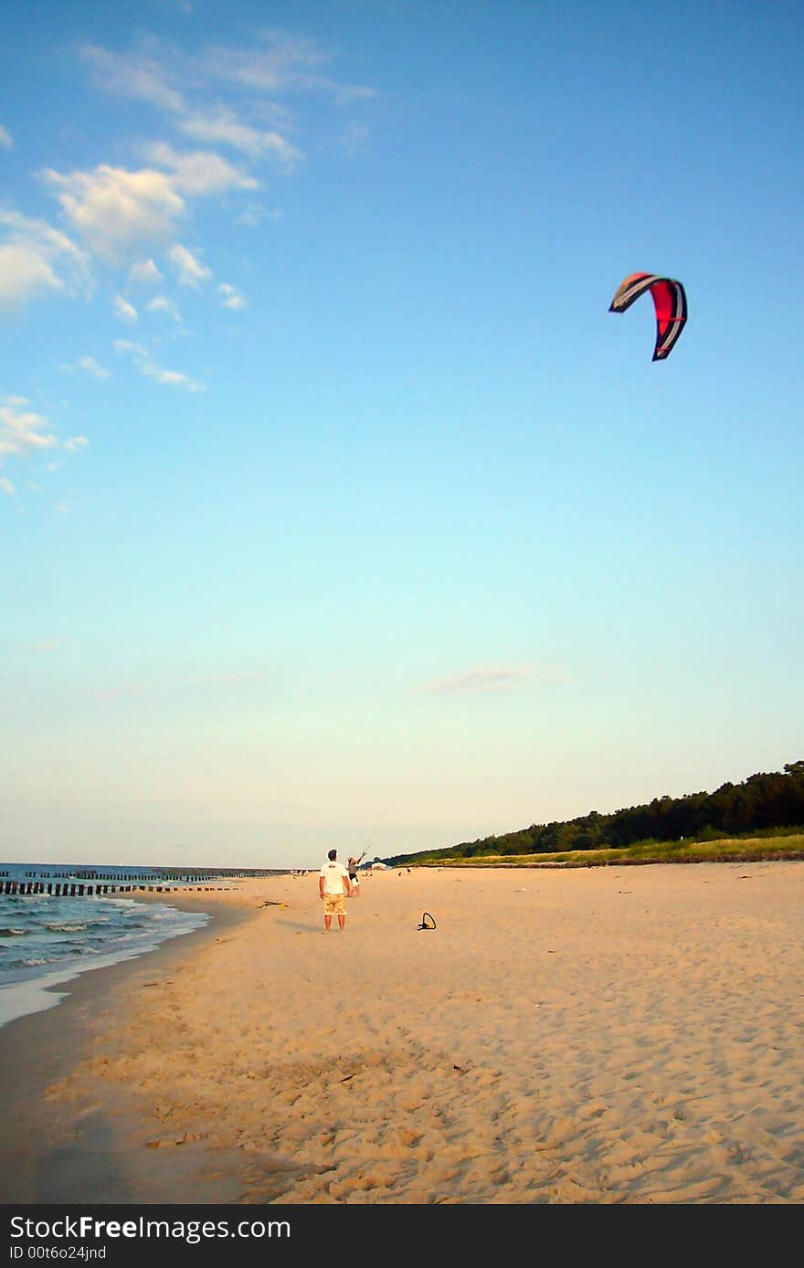 Kite-boarder trays to prepare his kite on a beach. Kite-boarder trays to prepare his kite on a beach.