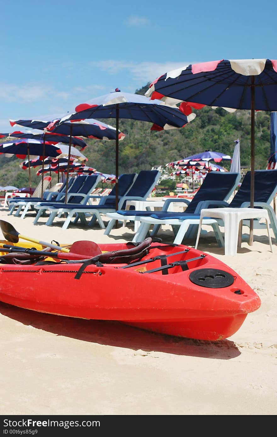 Red sea kayak on the beach surrounded by beach umbrellas.