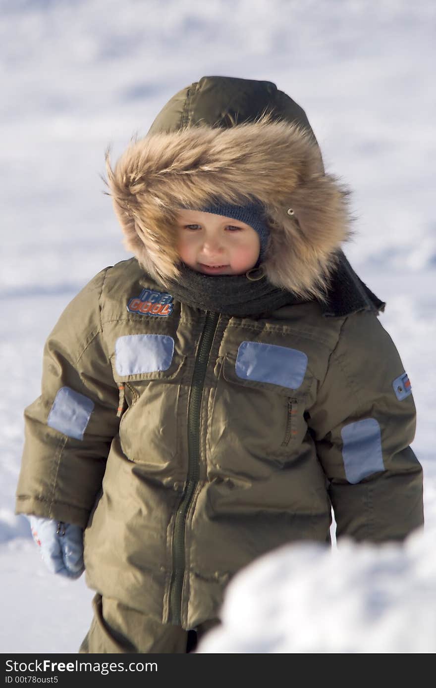 Little boy in a green arctic jacket with a collar et on to snow at the frozen lake. Little boy in a green arctic jacket with a collar et on to snow at the frozen lake