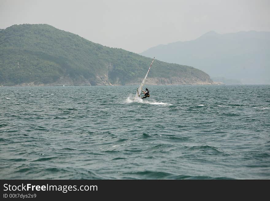 A single yatch across calm blue waters. A single yatch across calm blue waters