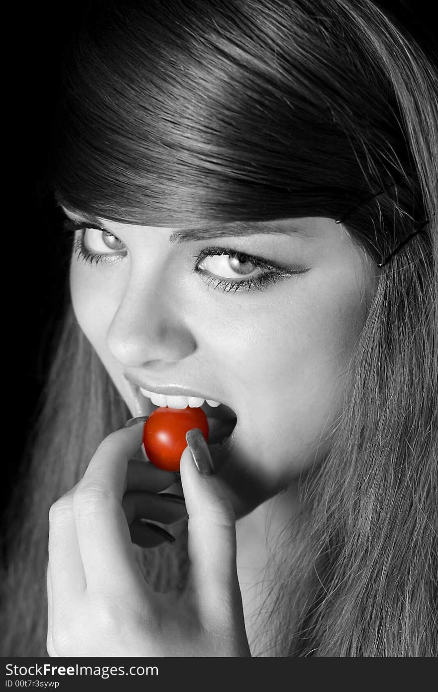 Beautiful young woman biting a tomato. Beautiful young woman biting a tomato