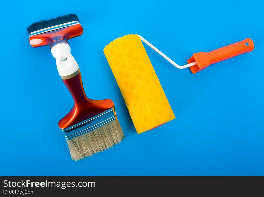 Paint brushes and paint roller on blue background. Paint brushes and paint roller on blue background