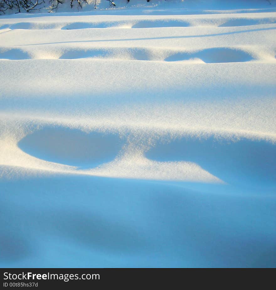 Foot prints in the snow with shadows on a snowy day in winter after a storm in wisconsin