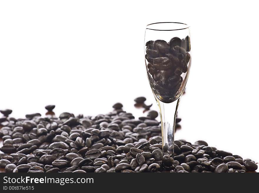 Spilled coffee beans isolated over white with shot glass. Spilled coffee beans isolated over white with shot glass