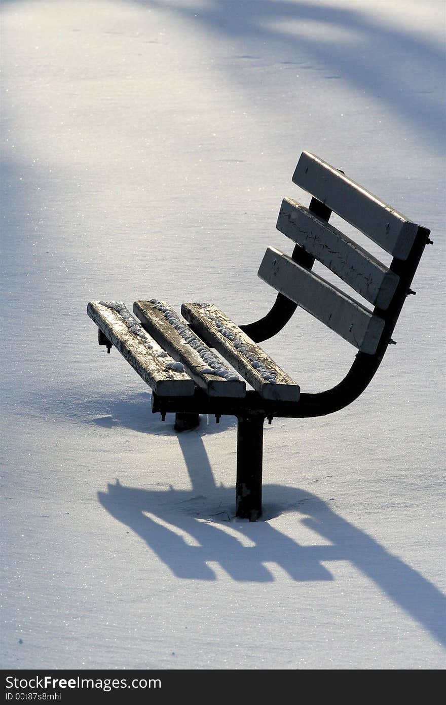 Isolated park bench in winter with long casted shadows. Isolated park bench in winter with long casted shadows.