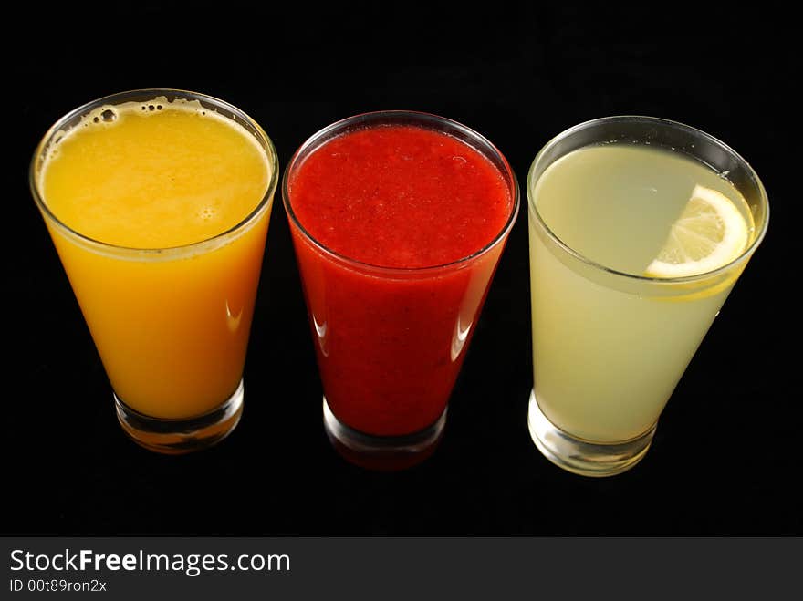 Three cups of juice isolated by black background