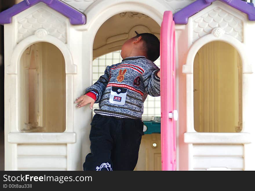 A naughty Chinese boy play happily in the kindergarten doll house, colorful plastic doll house. A naughty Chinese boy play happily in the kindergarten doll house, colorful plastic doll house