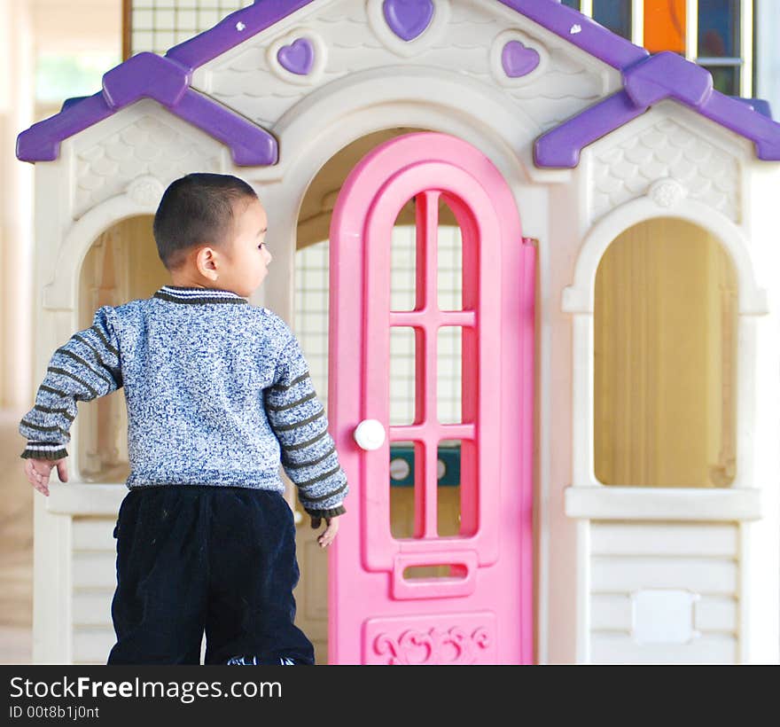 A Chinese kid of three years old play before a colorful plastic doll house. A Chinese kid of three years old play before a colorful plastic doll house.