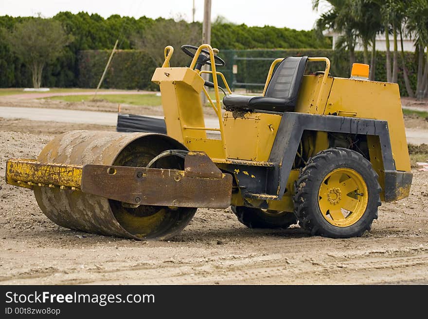 A small asphalt roller sits idle