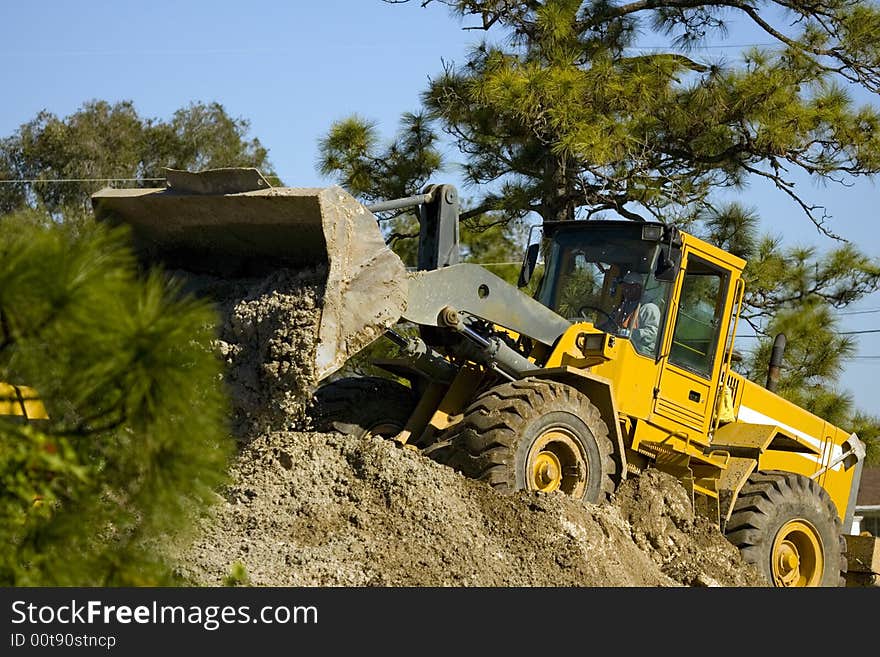 A front-end loader hard at work moving dirt. A front-end loader hard at work moving dirt