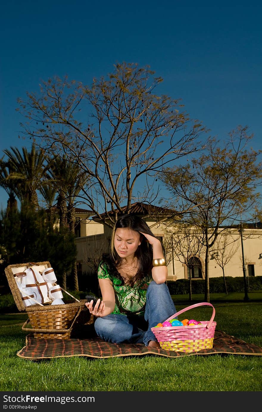 Asian female looking at her phone waiting for boyfriends call because he is late for their spring picnic. Asian female looking at her phone waiting for boyfriends call because he is late for their spring picnic.