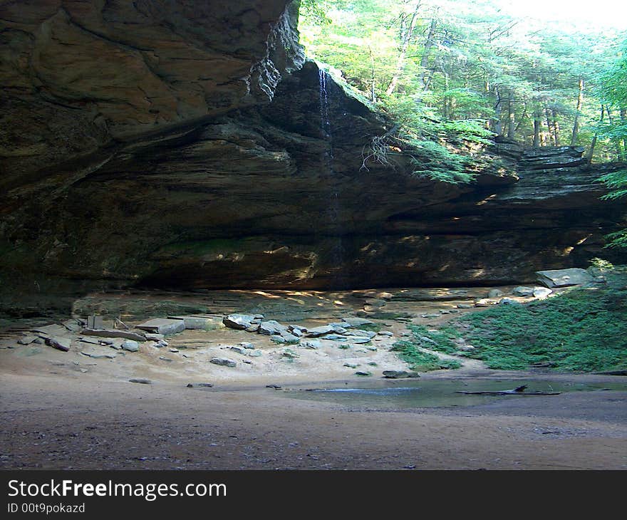 Dramatic rock overhang with small 50 foot waterfall. Dramatic rock overhang with small 50 foot waterfall