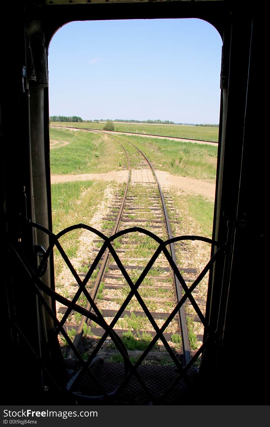 Railway tracks stretching off around a bend from the door of the last car. Railway tracks stretching off around a bend from the door of the last car