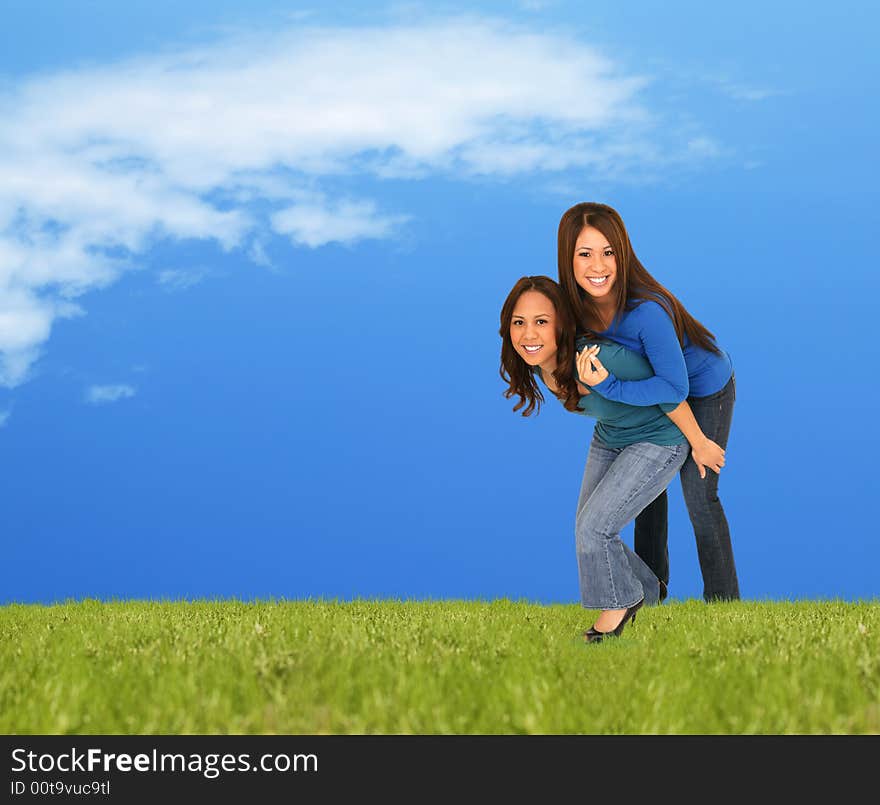 Two girls playing piggyback outside on the grass in beuatiful spring or summer shot. Two girls playing piggyback outside on the grass in beuatiful spring or summer shot