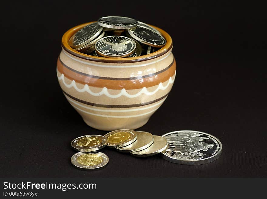 At the clay pot many silver coins lie, somewhat lies near the pot.