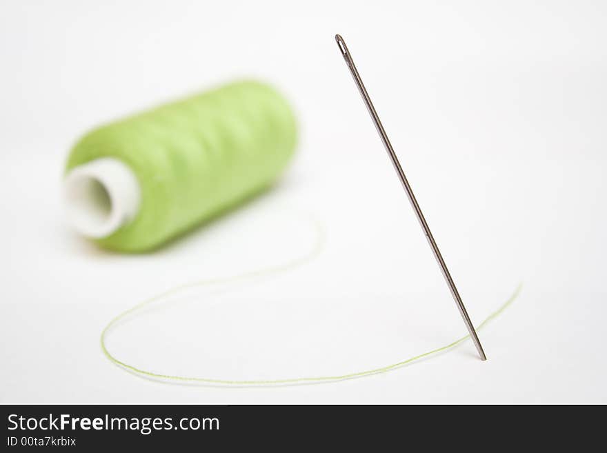 Green sewing and steel needle on a white isolated background