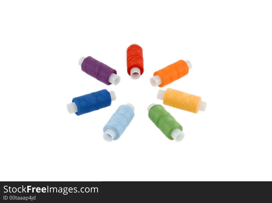 Seven sewing spools disposed as a circle in the spectrum order isolated over white. Seven sewing spools disposed as a circle in the spectrum order isolated over white