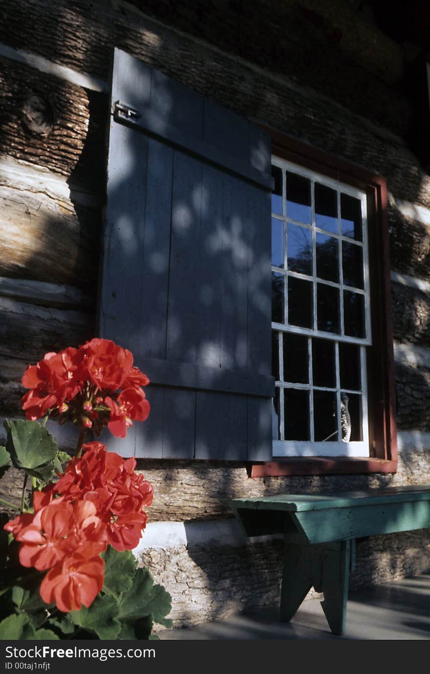 Flowers adorne the porch of a log cabin