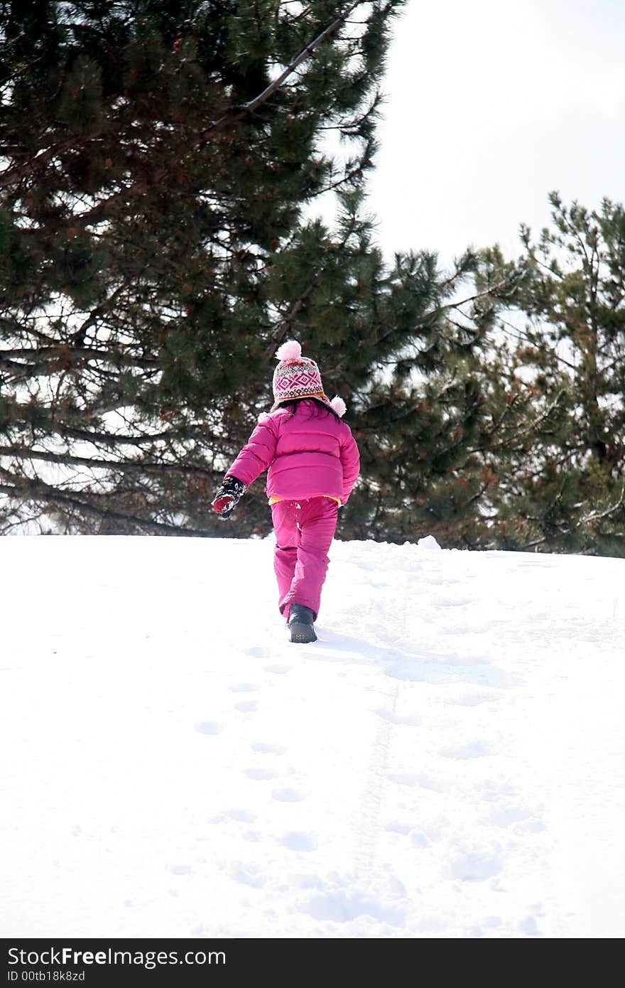 Preschooler walking up a snow covered hill.