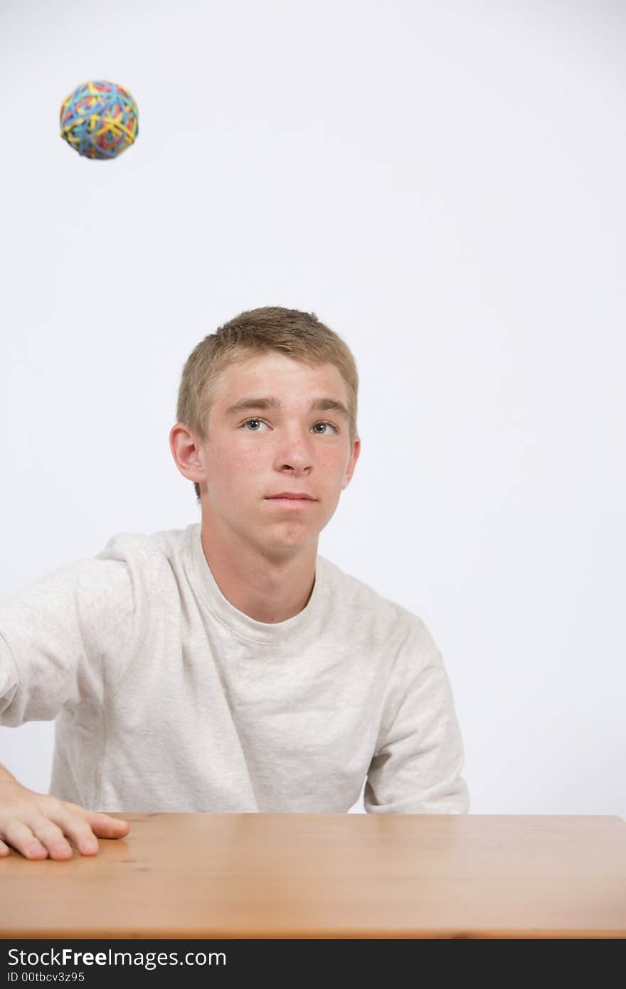 A teen age student playing with a bubber band ball in class