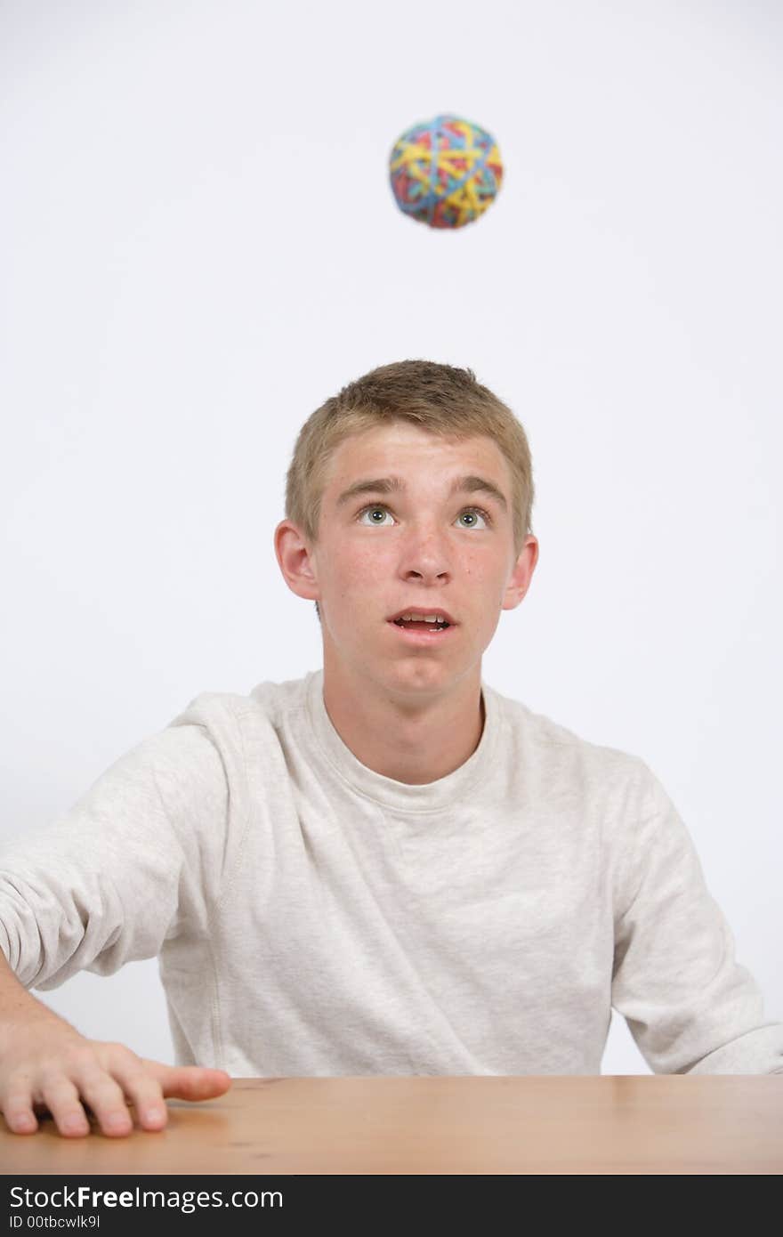 A teen age student playing with a bubber band ball in class