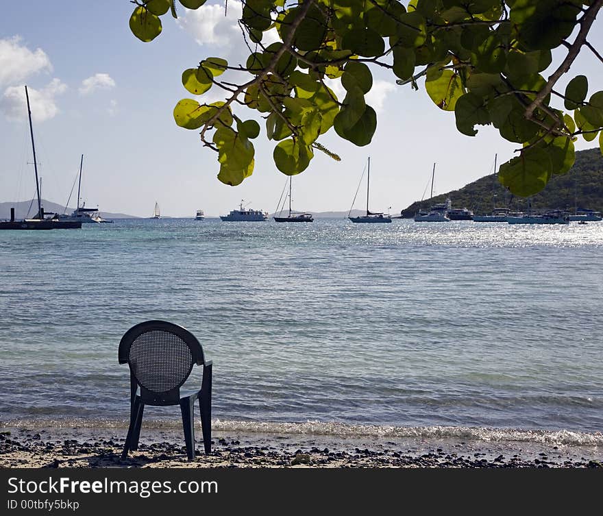 Empty chair on a beach with sailboats in the background. Empty chair on a beach with sailboats in the background.