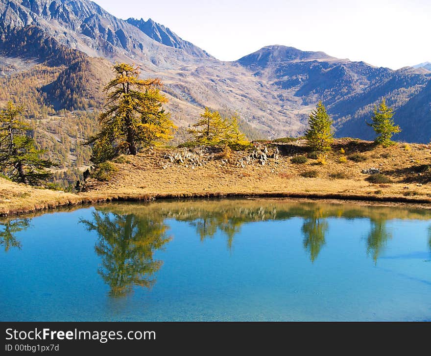 A mountain landscape with a lake, trees and reflections in the water. A mountain landscape with a lake, trees and reflections in the water.