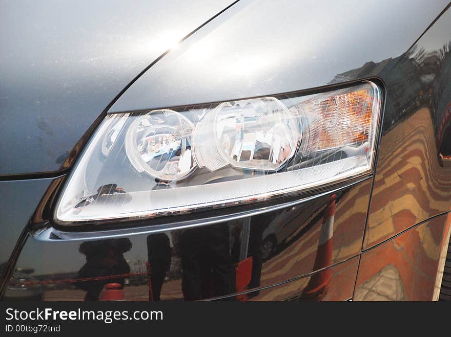 The headlight of a luxury car in the dazzling noon sun.