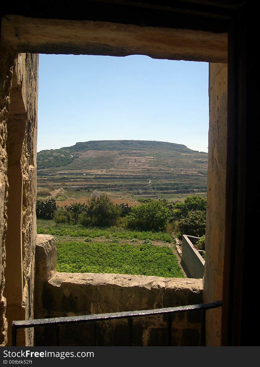 An old farmhouse window looks out over a farmer's field in the village of Gharb in Gozo, Malta. An old farmhouse window looks out over a farmer's field in the village of Gharb in Gozo, Malta