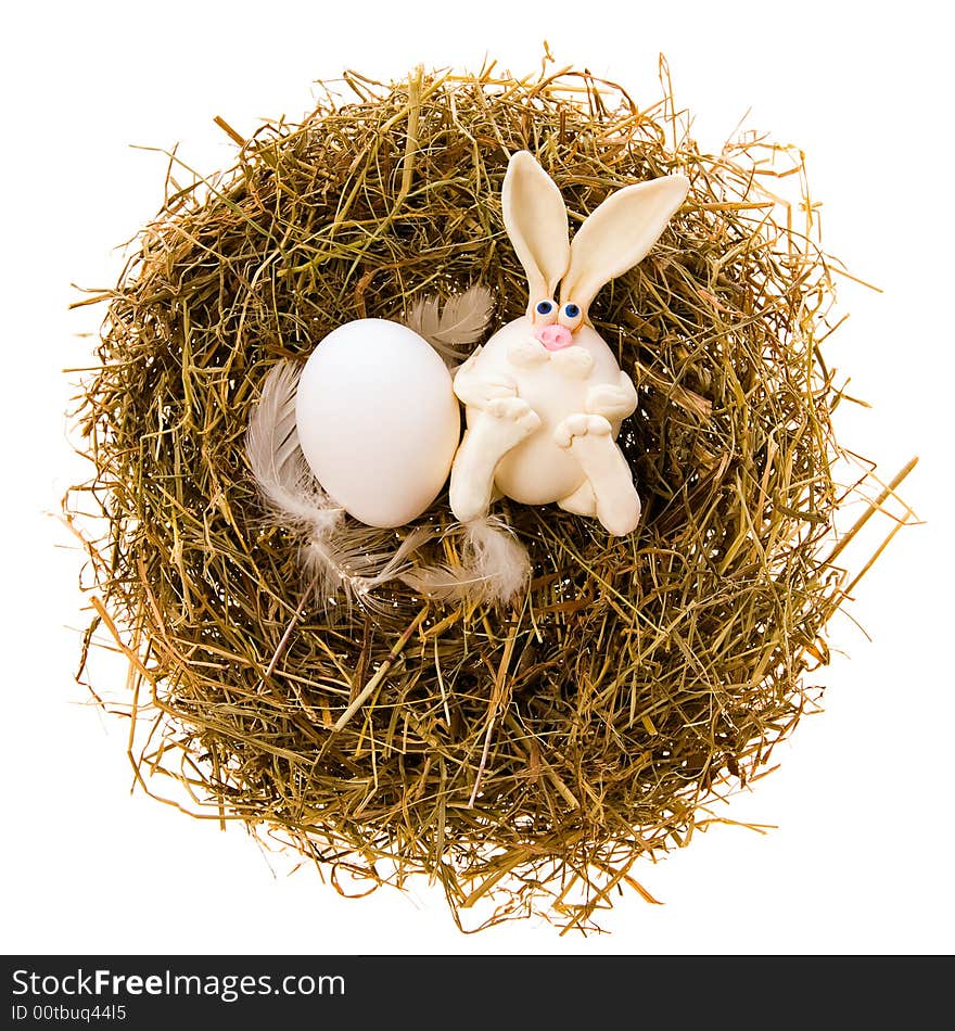 Easter white toy rabbit and white egg a nest from a dry grass on a white background. Easter white toy rabbit and white egg a nest from a dry grass on a white background