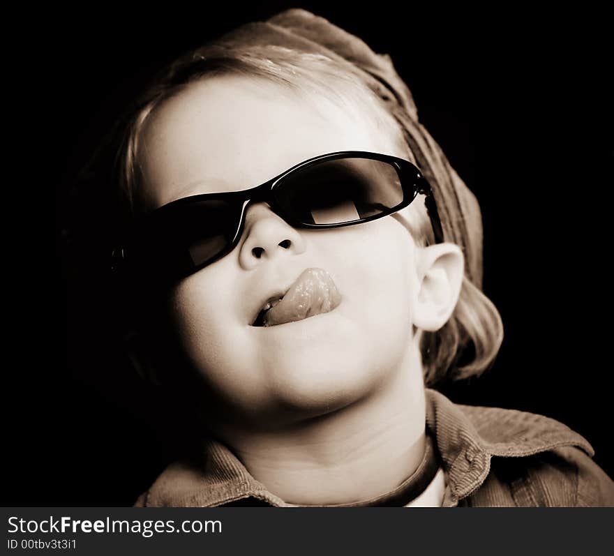 Little girl with sunglasses and a scarf sticking out her tongue. Little girl with sunglasses and a scarf sticking out her tongue