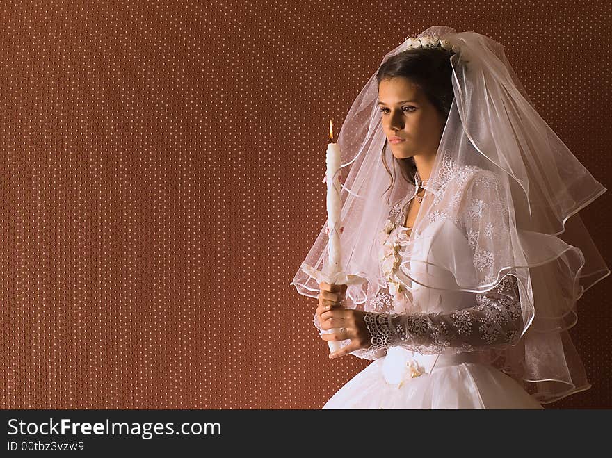 The wedding bride with a candle on brown background