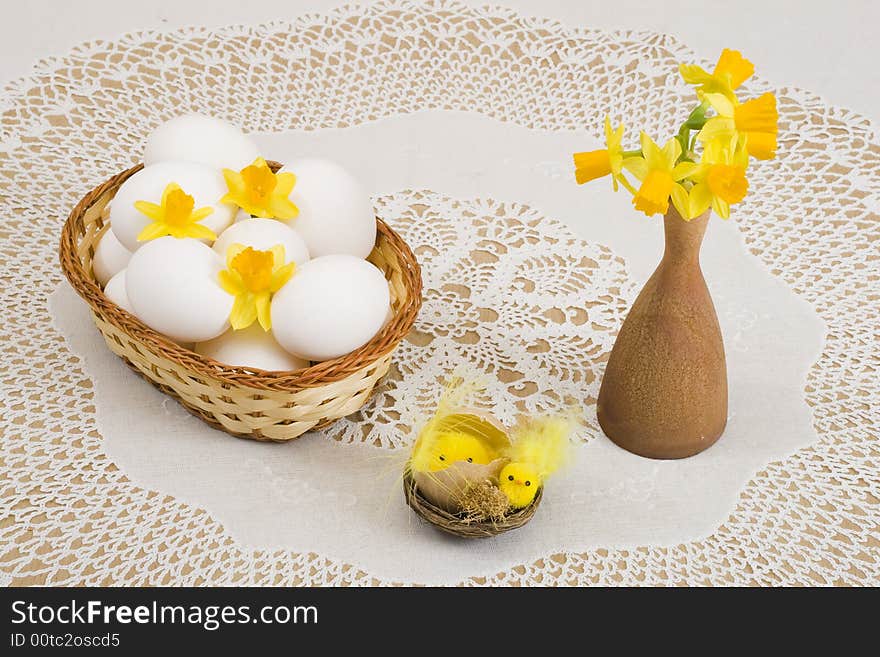 A basket of eggs, easter chicken and yellow daffodils