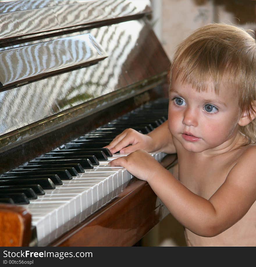 The little girl presses keys of the piano. The little girl presses keys of the piano