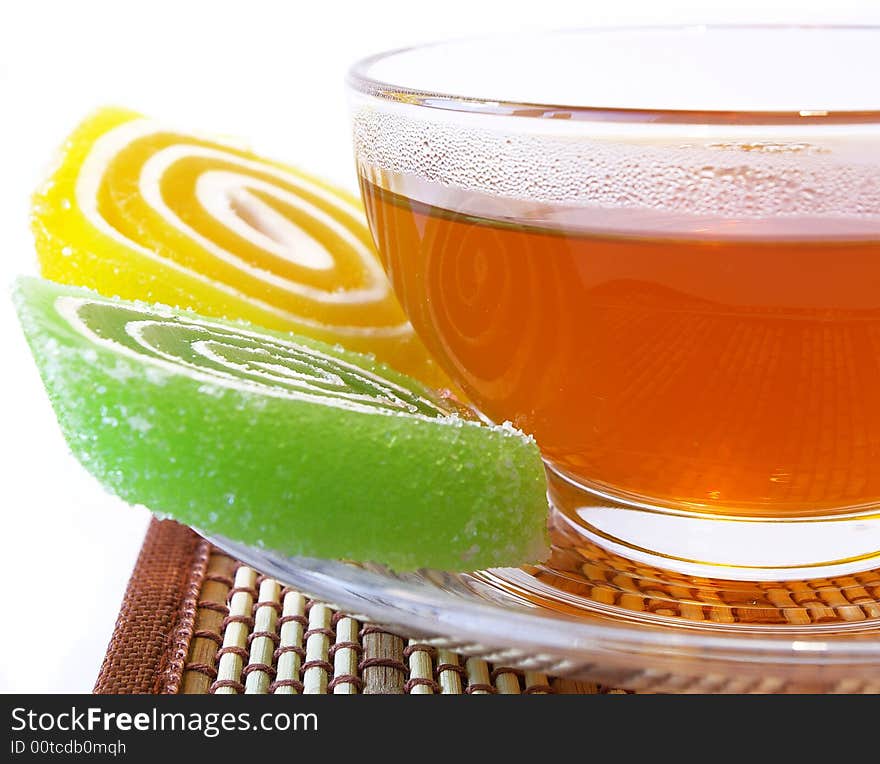 Multi-coloured fruit candy and cup of tea on a white background