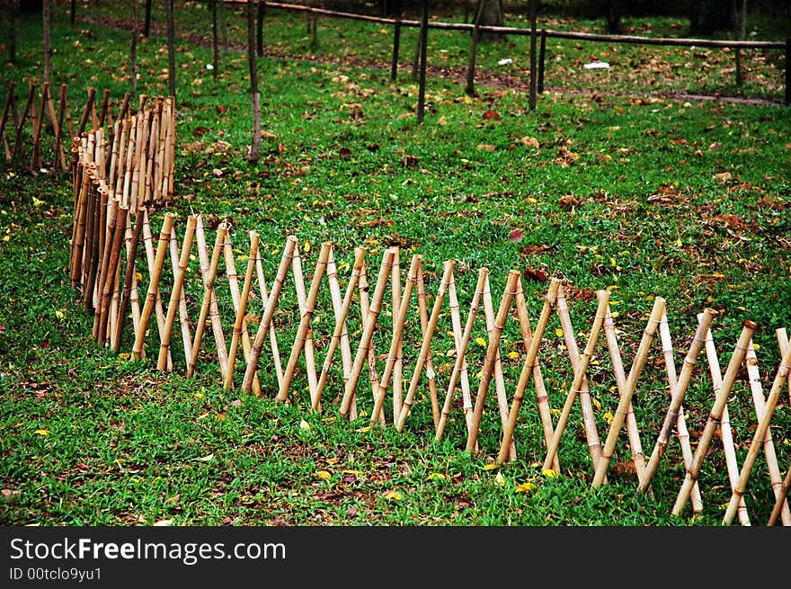 The fence made of bamboo on the green grass. The fence made of bamboo on the green grass.