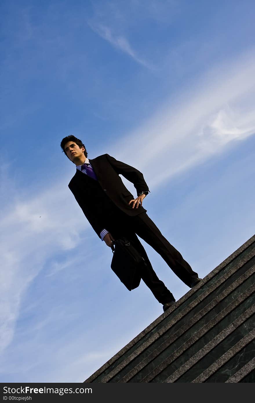 Businessman posing on stairs against blue sky. Businessman posing on stairs against blue sky.