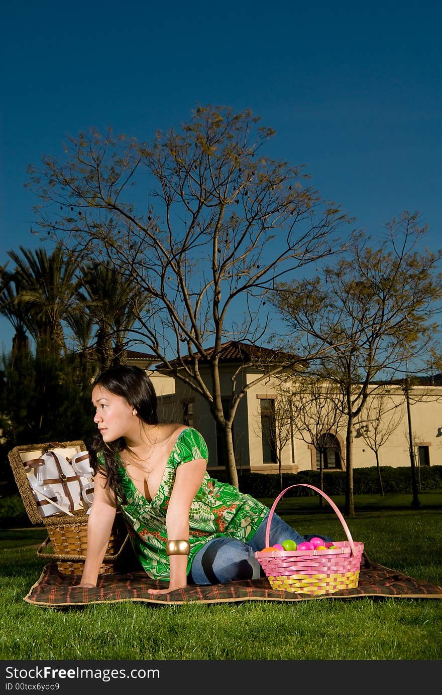 Asian female sitting on her picnic blanket surrounded by blankets looking to camera left. Asian female sitting on her picnic blanket surrounded by blankets looking to camera left.