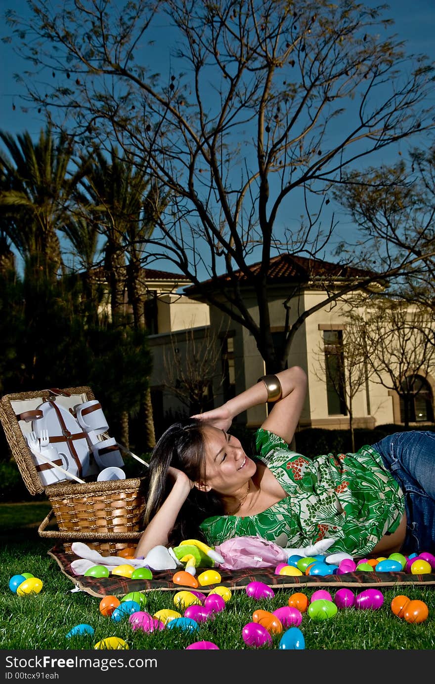 Asian female with her hands on her head laying on a picnic blanket. Asian female with her hands on her head laying on a picnic blanket